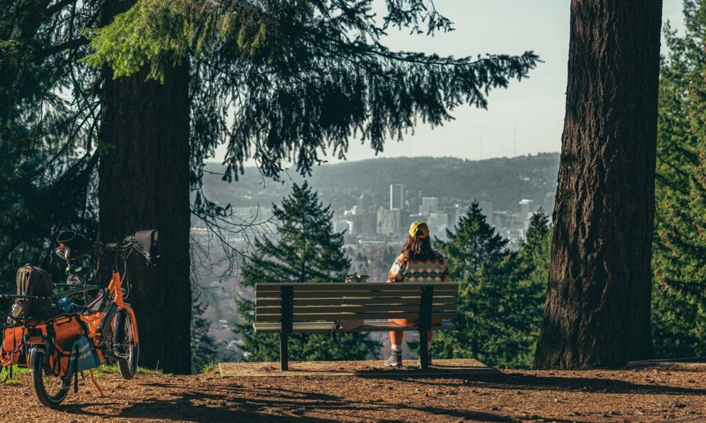 a person sits on a bench overlooking Portland at Mount Tabor Park
